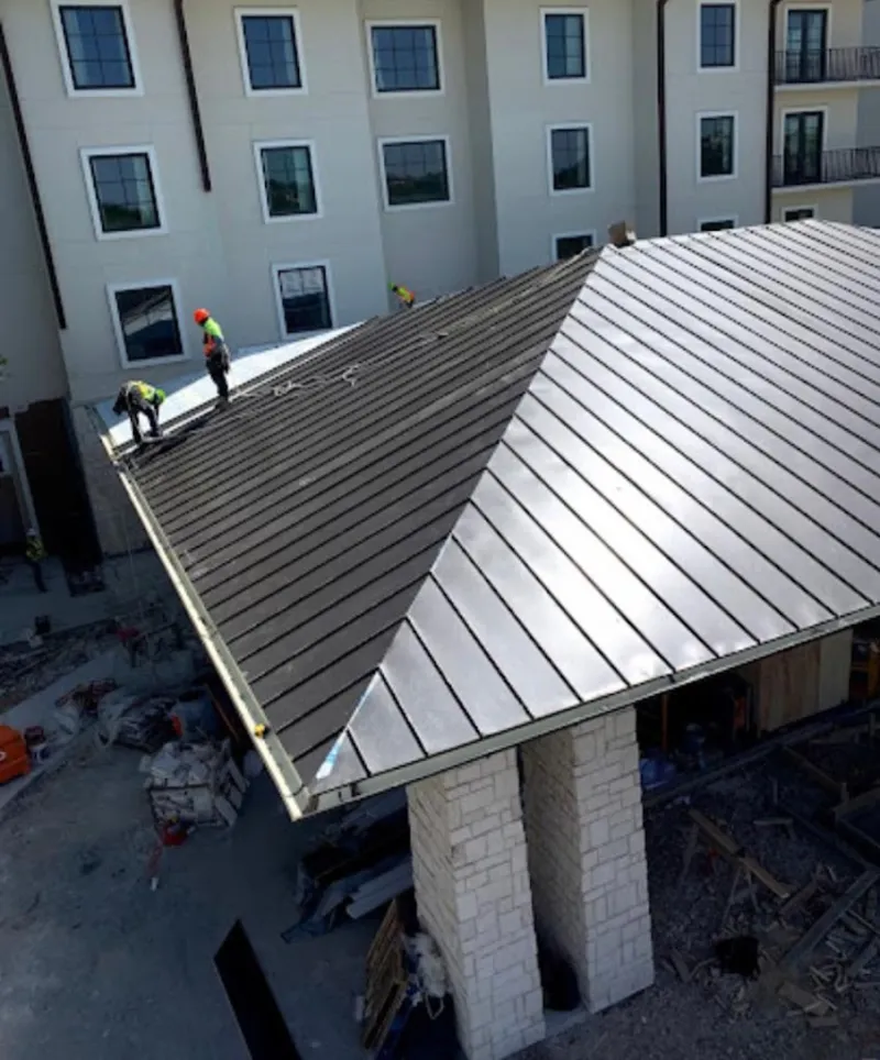 Crew installing standing seam metal roof panels on a commercial project in Jasper